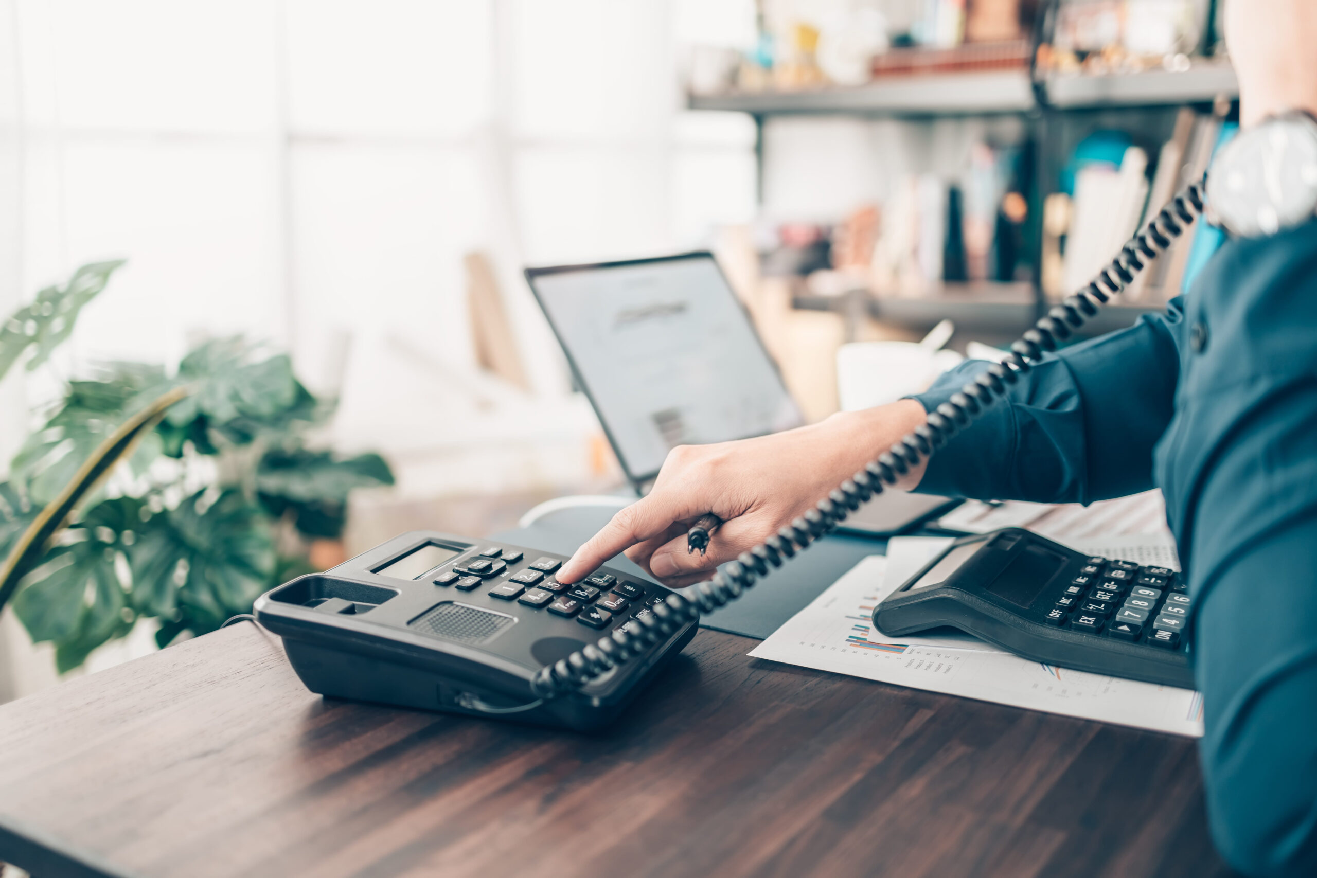 Office Worker Dialing A Desk Phone
