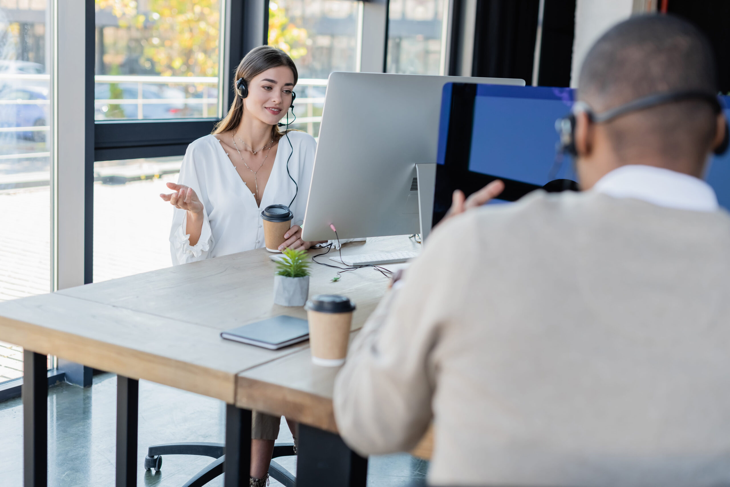 Customer Support Representatives Wearing Headsets Working At Computers In An Office